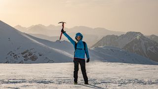 how to use an ice axe: mountaineer holds axe aloft