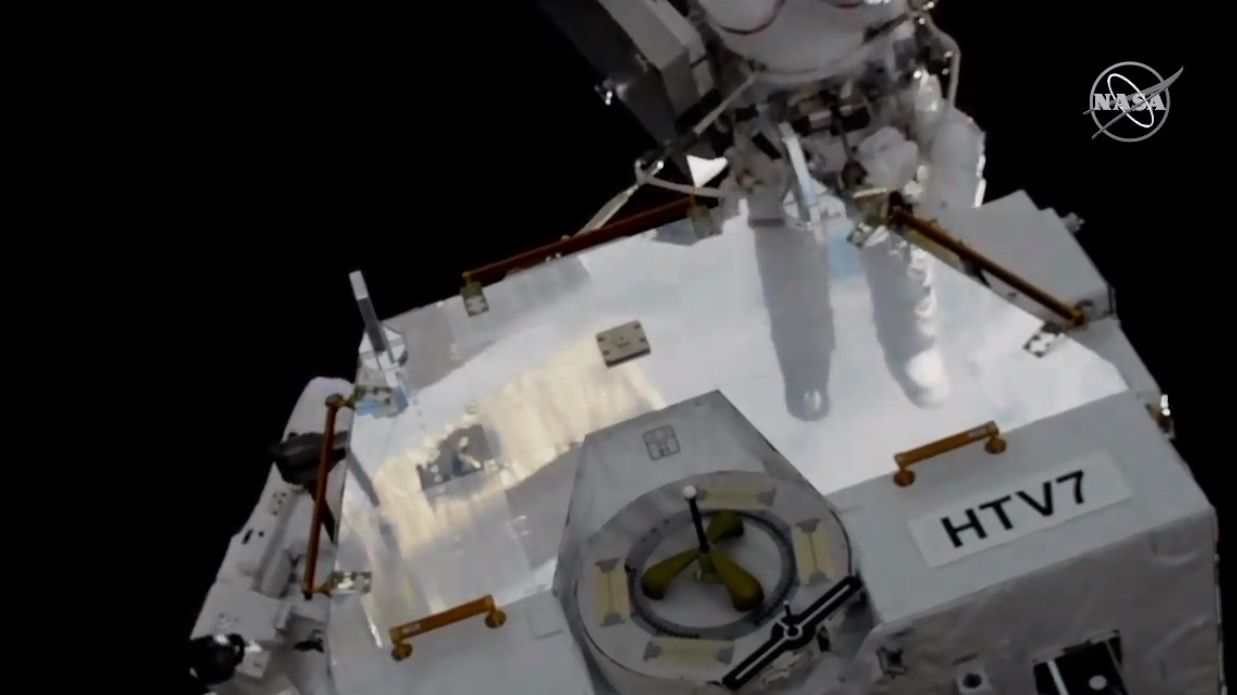 NASA astronaut Anne McClain's reflection is visible on the surface of the HTV-7 external palette.