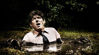 A man wearing a shirt and tie shoulder deep in quicksand