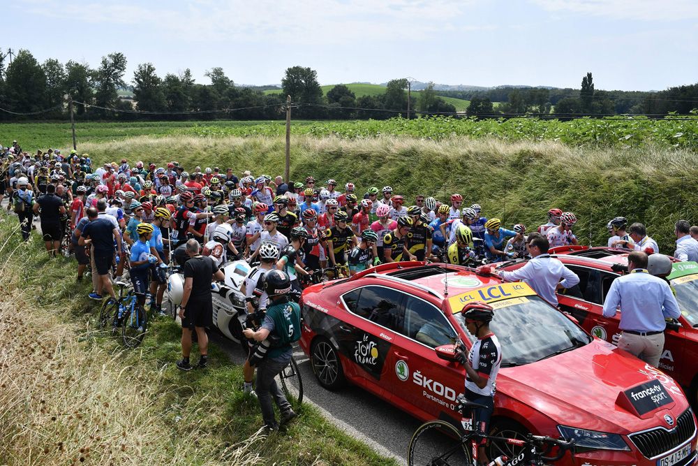 The Tour de France peloton was stopped behind the race director's car