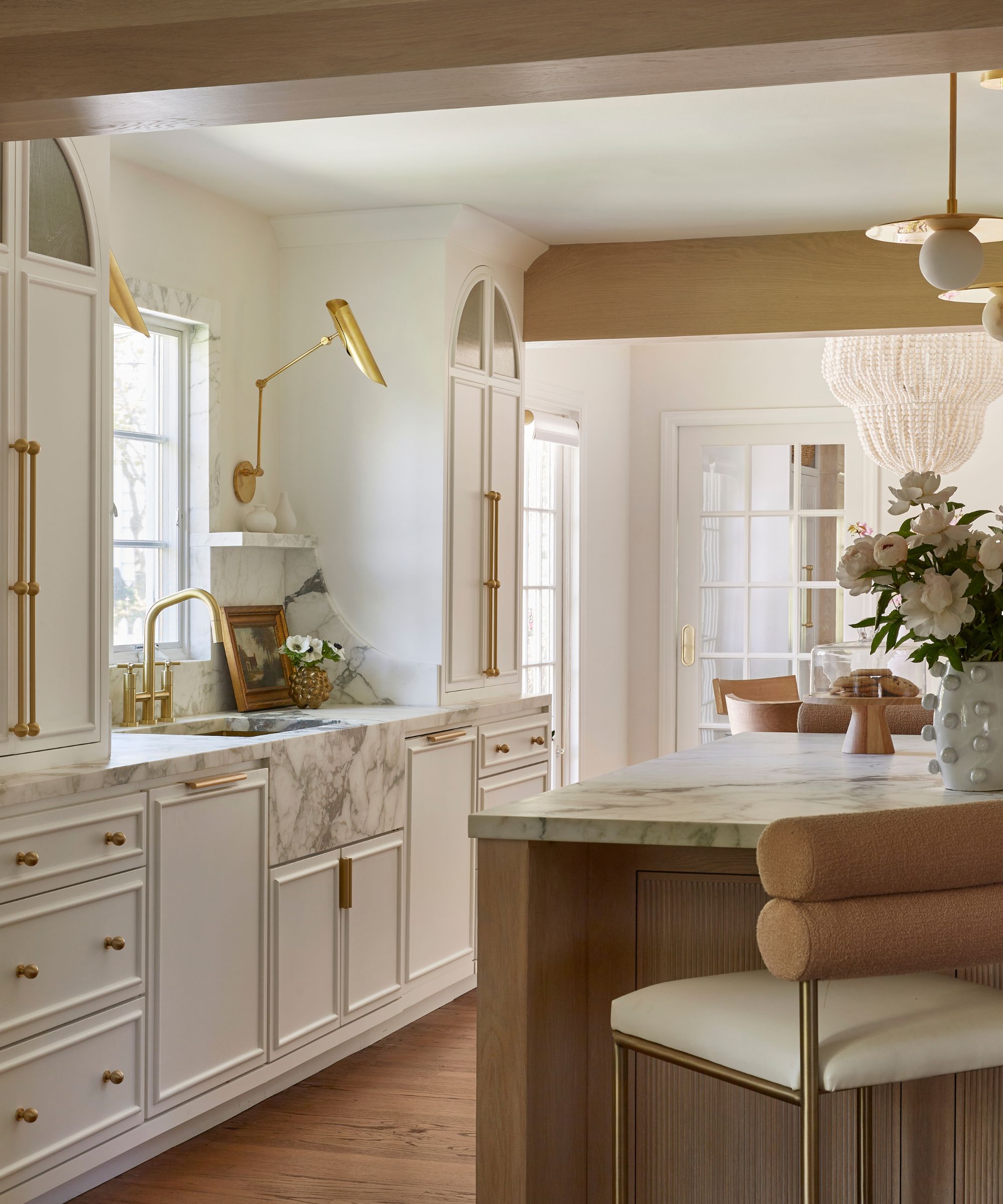 A white kitchen with a marble sink, marble countertops, and a marble window trim