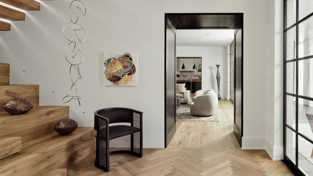 hallway with white walls, herringbone oak floors, oak staircase, black hallway, black armchair, steel frame windows