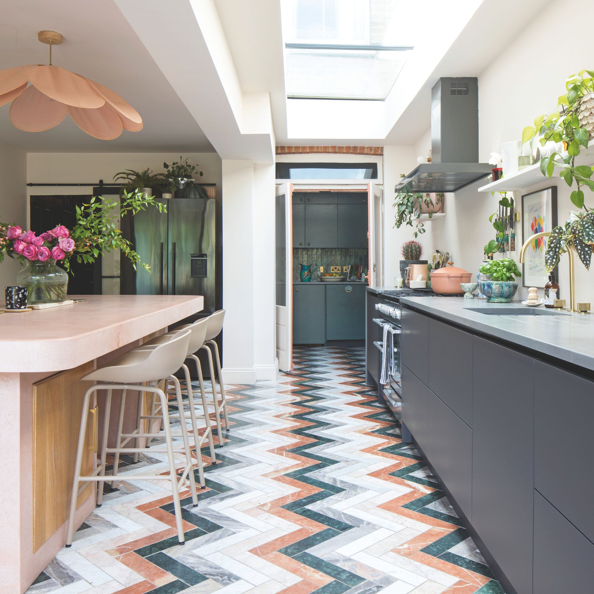 Kitchen with colourful zigzag tiles on the floor, grey cabinets on the right and a kitchen island on the left