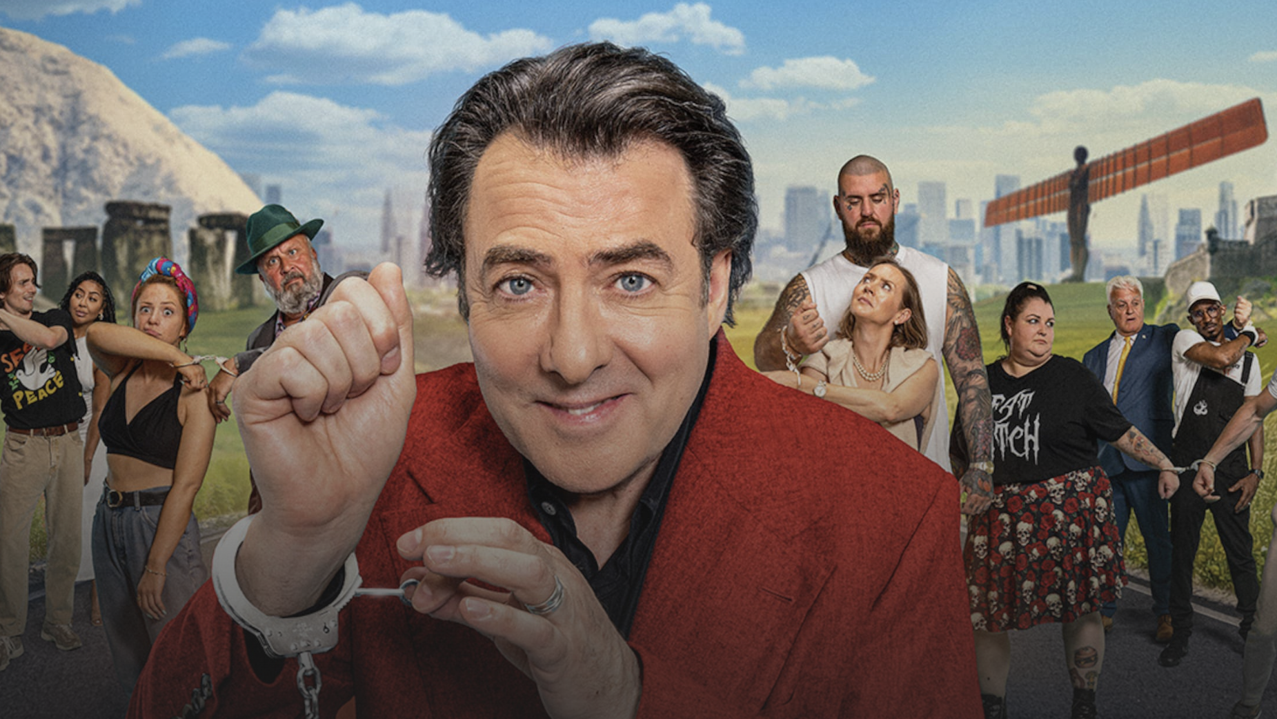 Jonathon Ross in red suit brandishes metal handcuffs in his new TV show Handcuffed: Last Pair Standing (2026) in the UK