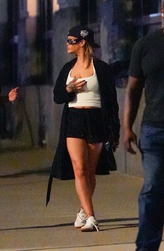 Rihanna wearing a white tank top, a black robe, black shorts, and Puma sneakers in New York City July 2024