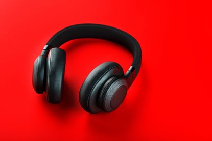 Black wireless headphones on a red background