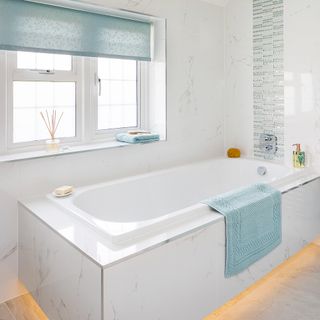 white and pale blue bathroom with lighting the under rim of a bath panel