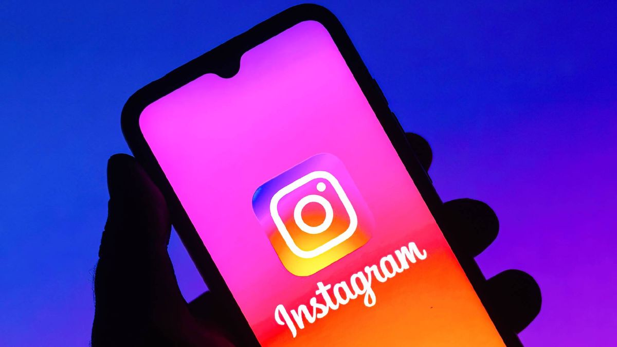 Man holding phone with Instagram logo on display with a blue background