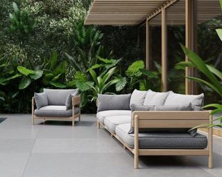 A Japanese-inspired teak wood outdoor sofa and lounge chair beside a tropical pool