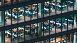 An aerial shot of an empty office building, full of desks and monitors to show a lack of workers in the office and inversely represent return to office mandates.