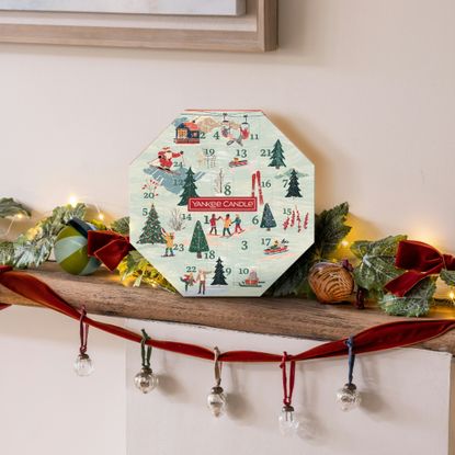 Yankee Candle Advent Wreath on a mantelpiece with a decorated Christmas garland