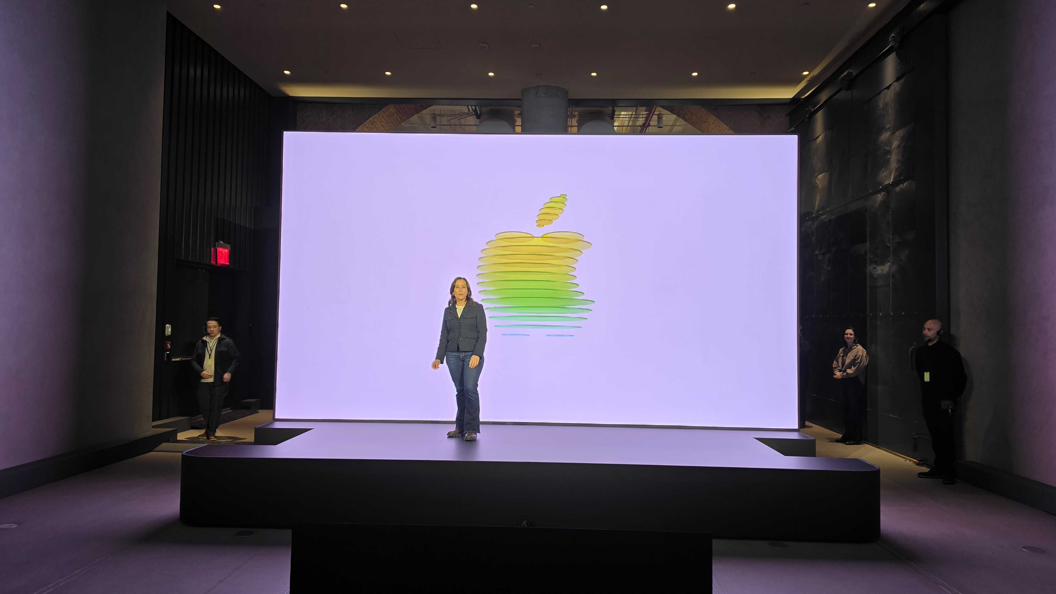 A woman stands on stage in front of an Apple logo