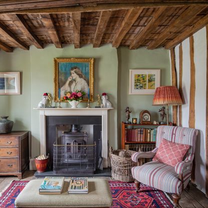 Living room in a tudor house with beamed ceiling, traditional fireplace and chair beside