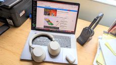 Listing image for best headsets and headphones for working from home showing Sony WH-1000XM5, AirPods Pro 2 placed on a MacBook laptop at a desk