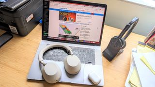 Hero image for working form home headphones showing Sony WH-1000XM5, AirPods Pro 2 placed on a MacBook laptop at a desk