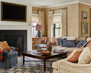 Living room dressed in rich floral pattern with neutral couches, drapes and cozy elements