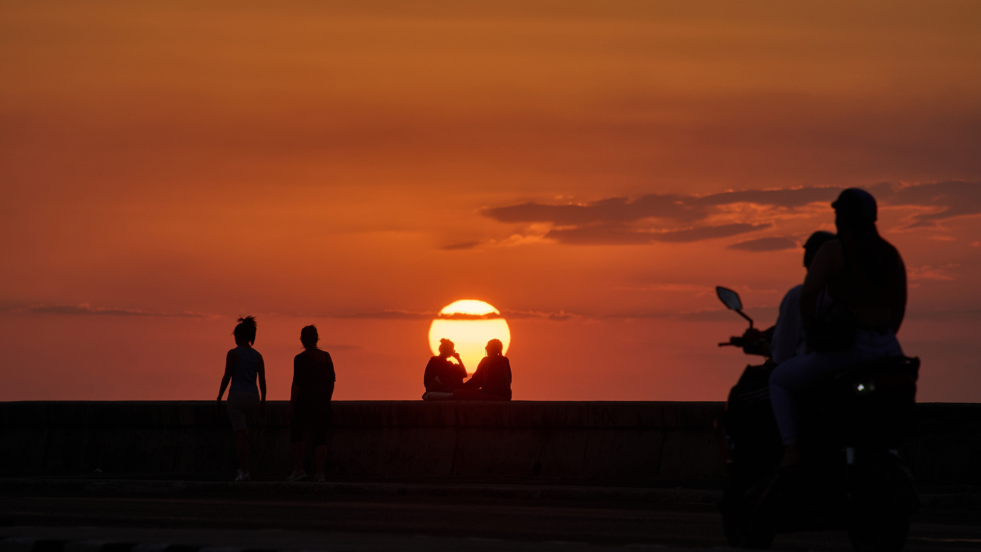 People spend the afternoon on the waterfront at sunset, in Havana, Cuba