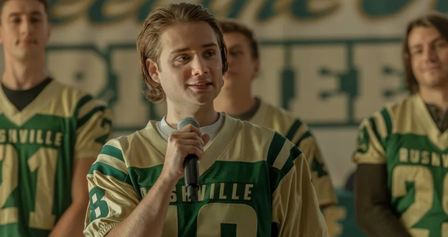 a blond-haired youth in a high school football jersey
