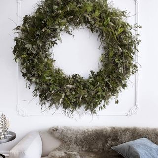 grey sofa under oversized wreath hanging on white wall in living room
