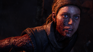 Senua looks to the camera, as the dark rot visibly crawls up her arm into her face.