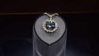 A large blue diamond encircled with smaller white diamonds as see at a museum. 