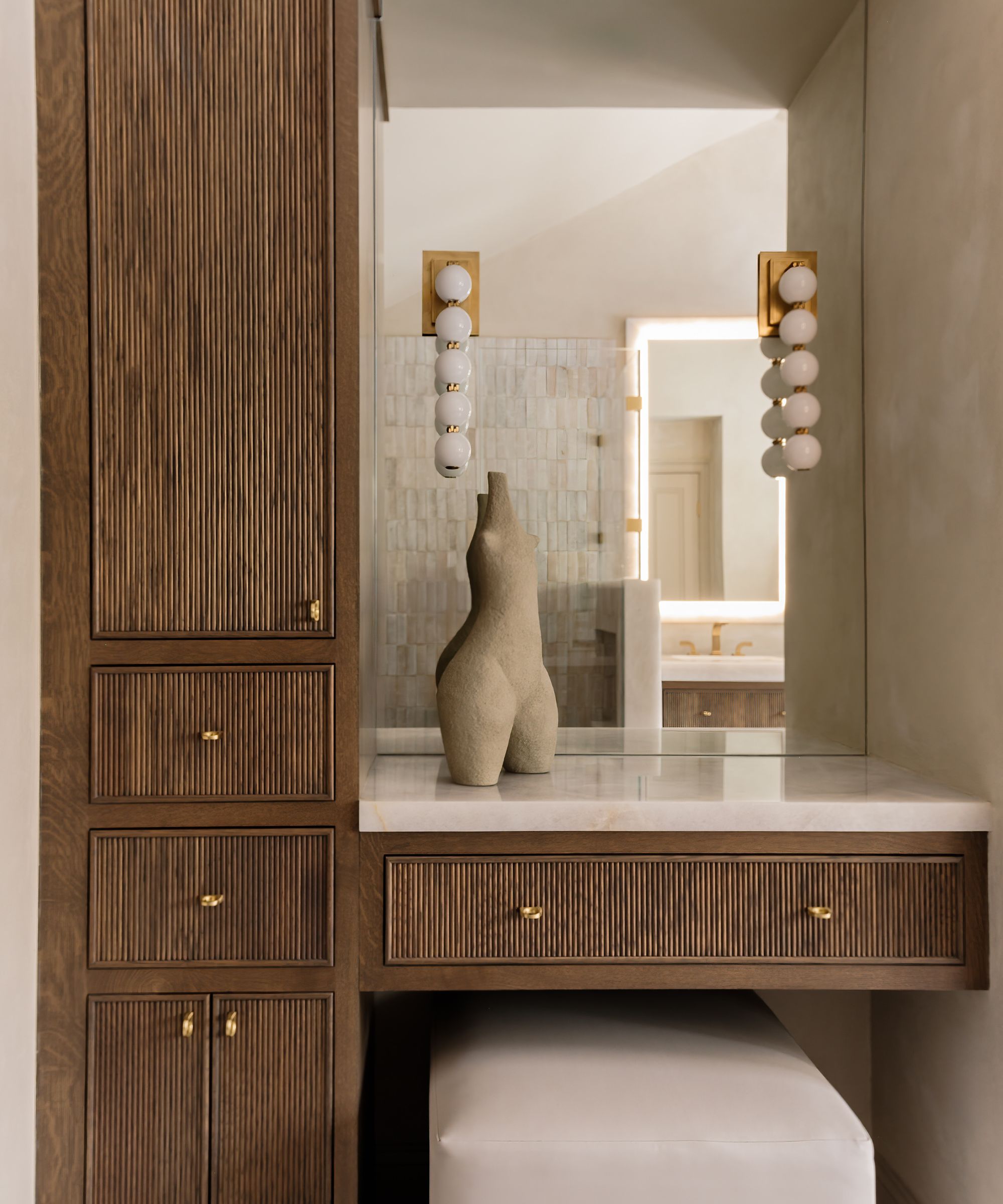 Vanity area with reeded wooden cabinets and a mirror with statement lighting