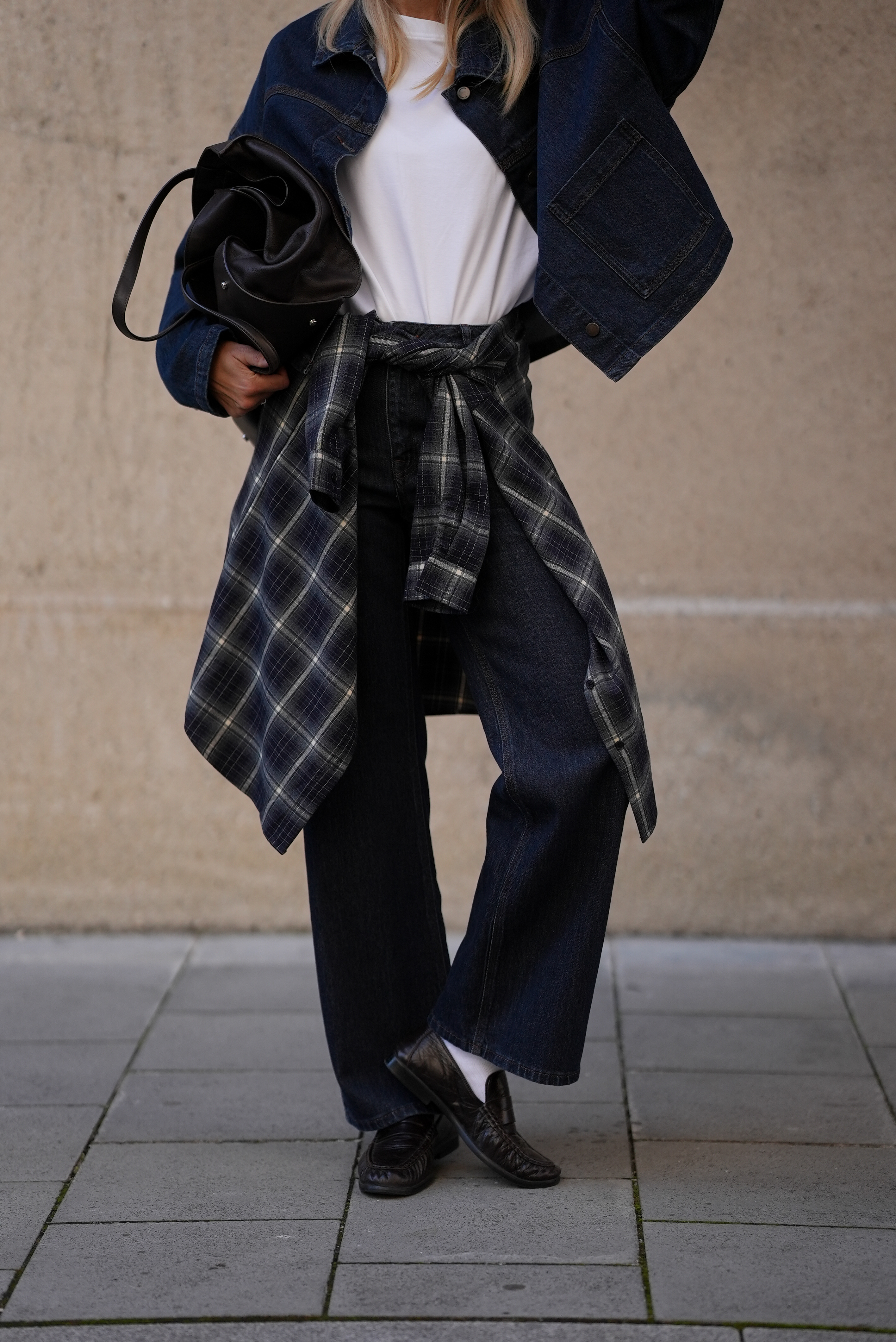 A woman wears a plaid shirt tied around her waist.