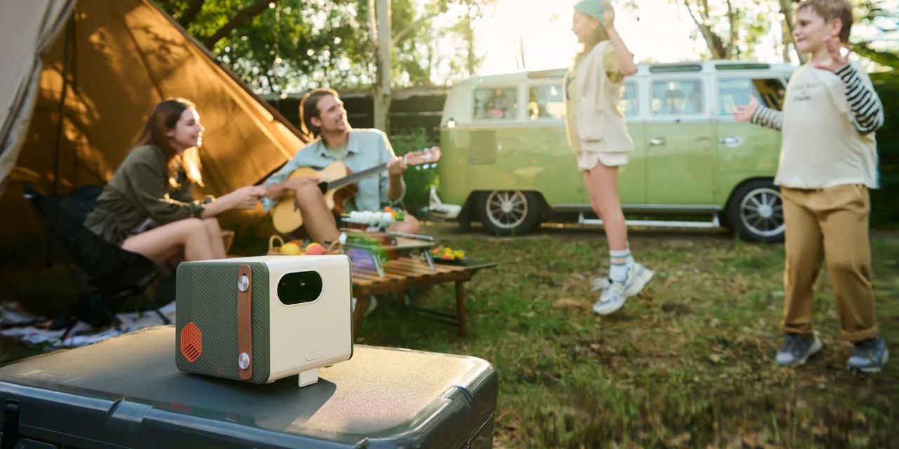 BenQ GS50 Wireless Projector on outdoor table with family on camping trip in the background