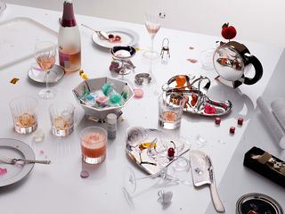 Christofle silver collection and tableware on white table cluttered with food and drink