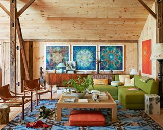 seating area with pine cladding, green modular sofa, blue patterned rug, statement artwork and wooden coffee table