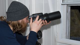 Man holding Nikon P1000 on a tripod by a window