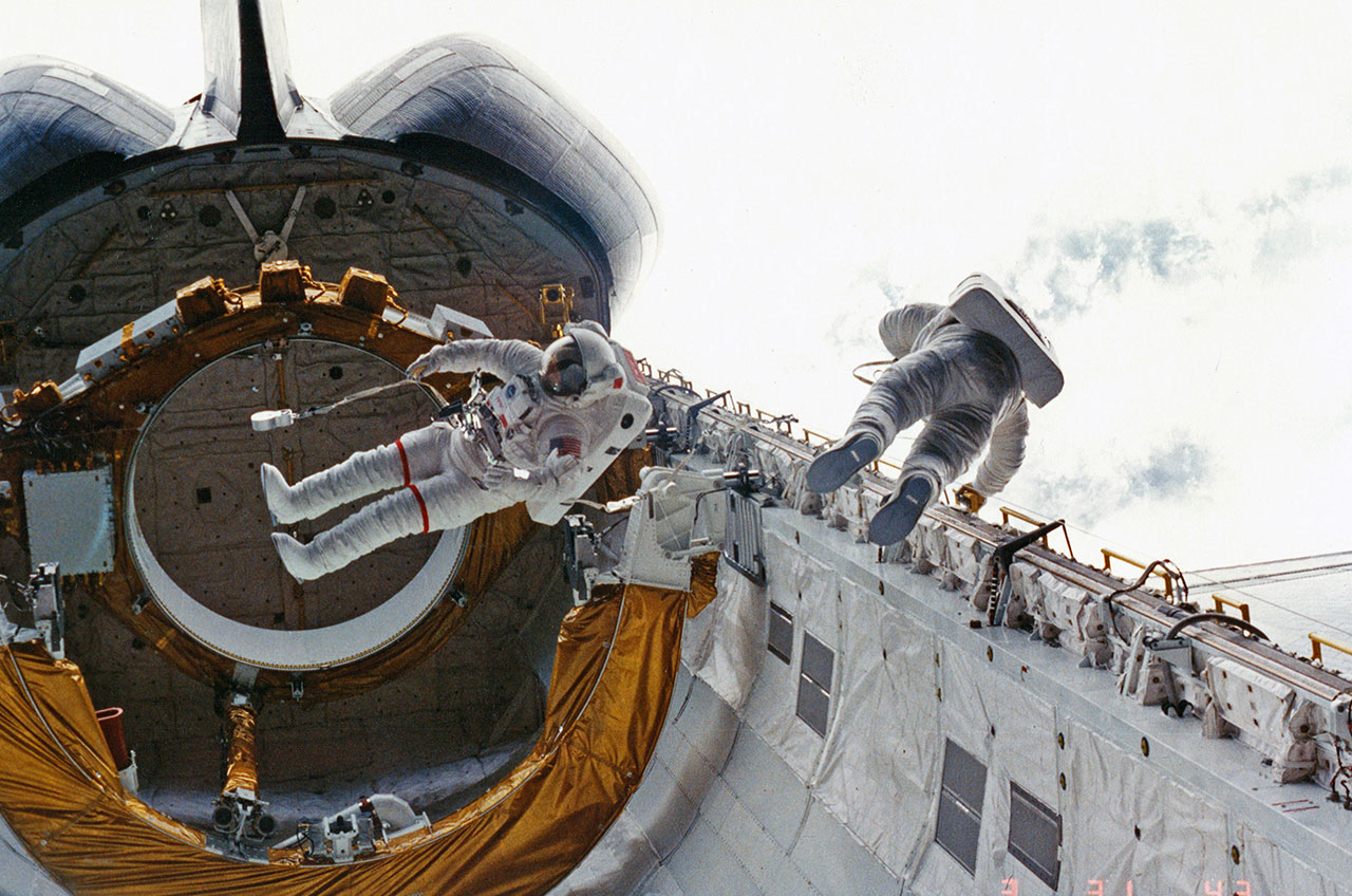 STS-6 crewmates Don Peterson (at right) and Story Musgrave perform the first shuttle-era spacewalk outside Challenger in 1983. 