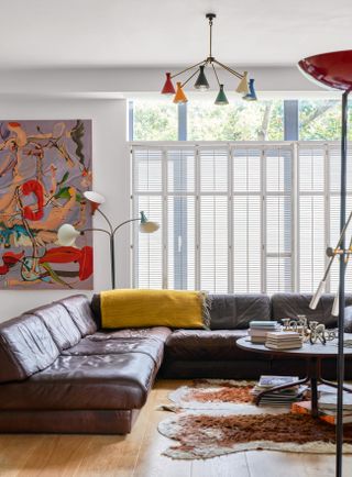 Living room with large leather sofa,, bright artwork and statement lighting
