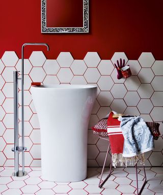 Bathroom with modern looking sink and tap with red walls and white tiles