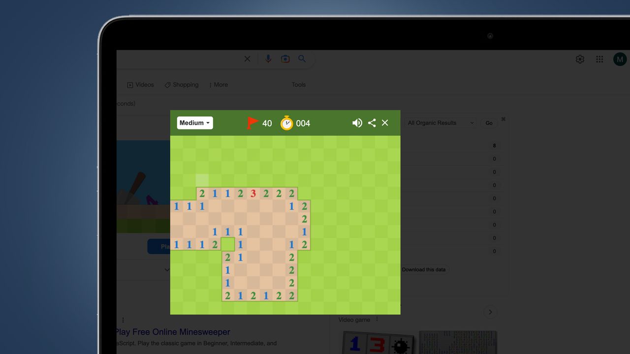 A laptop screen on a blue background showing Google's Minesweeper game