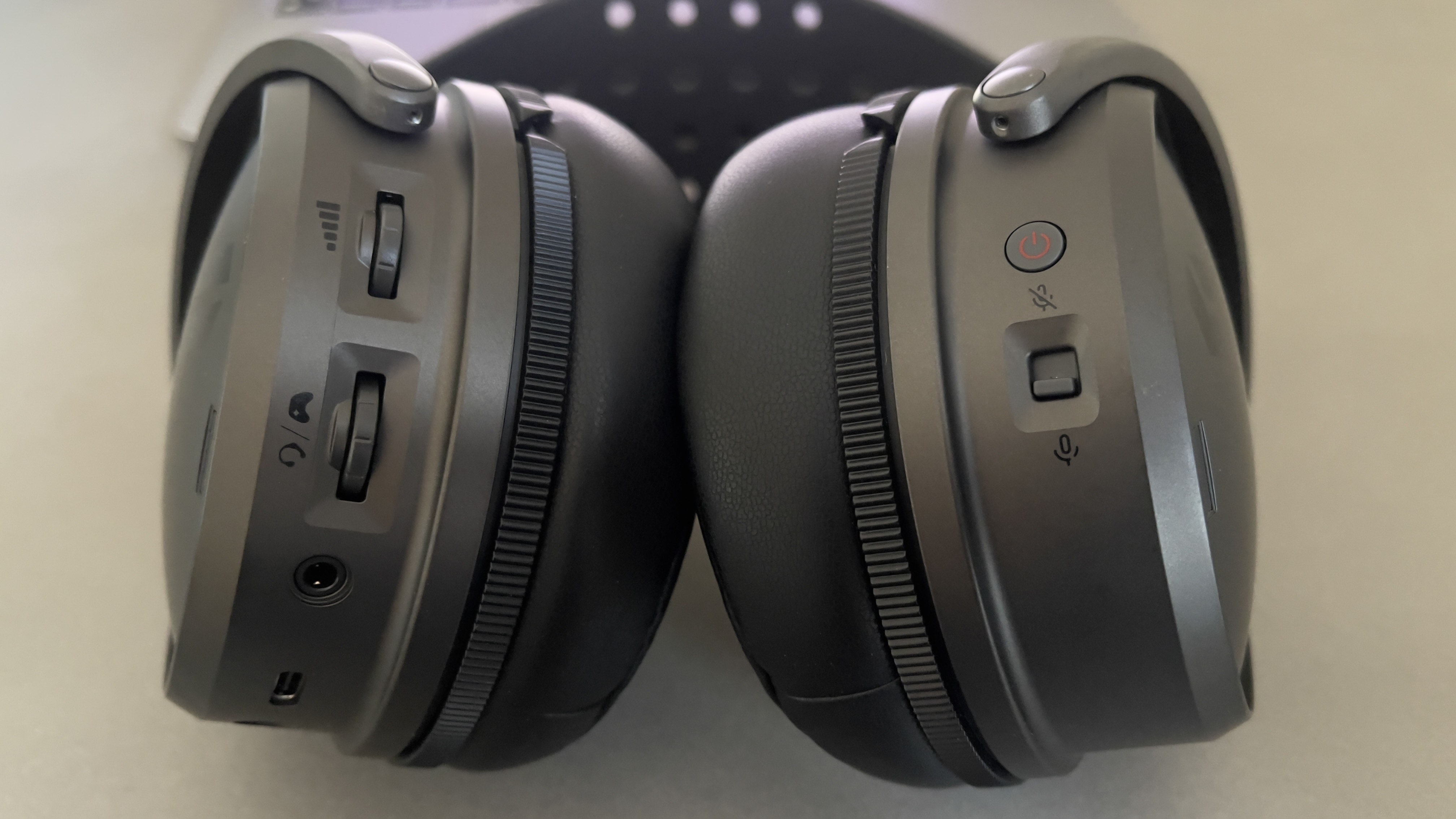 The Audeze Maxwell 2 gaming headset lying on a pale desk with a close-up view of its buttons