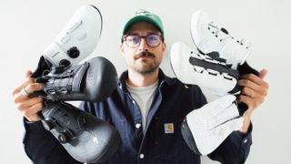 A man holds a selection of wide road cycling shoes