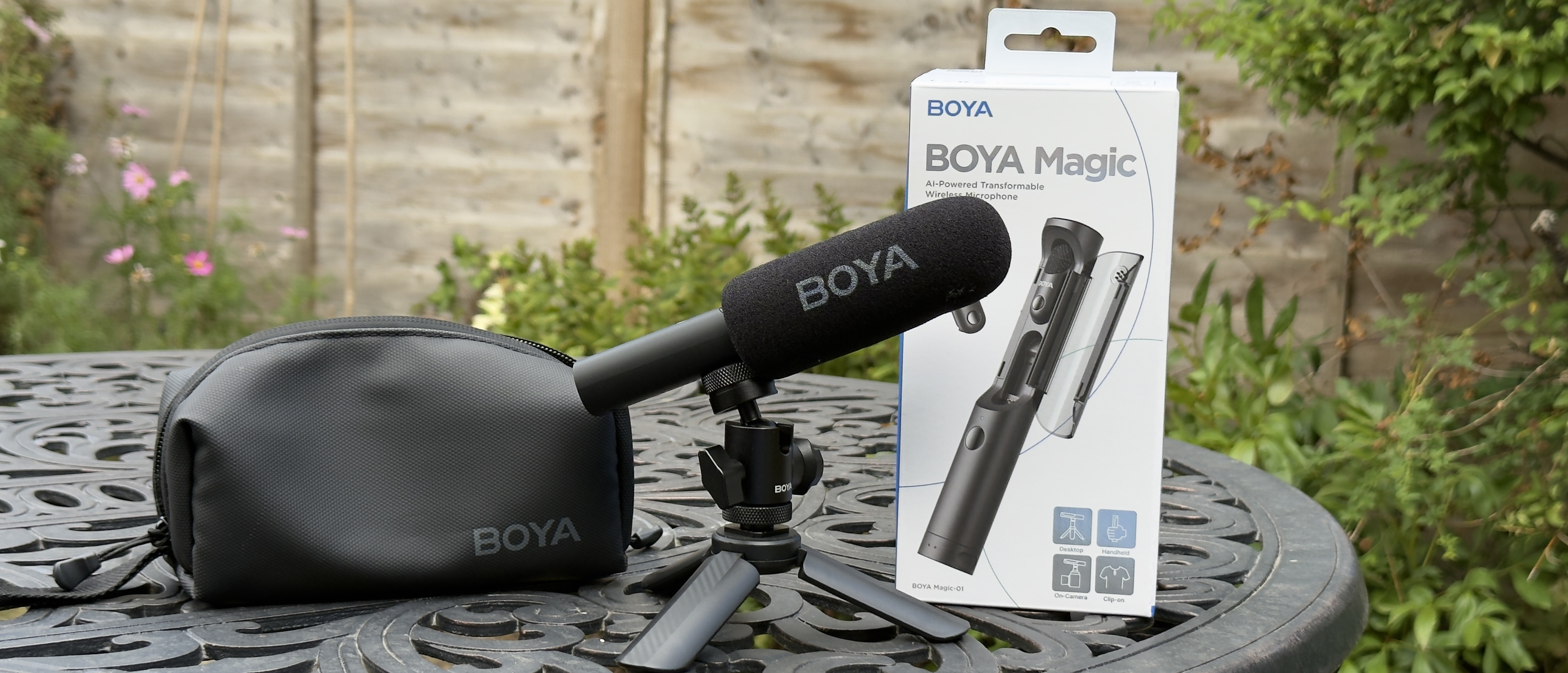 Shot of the Boya Magic’s gun mic configuration on a mini tripod sitting on a desktop adjacent to a laptop.