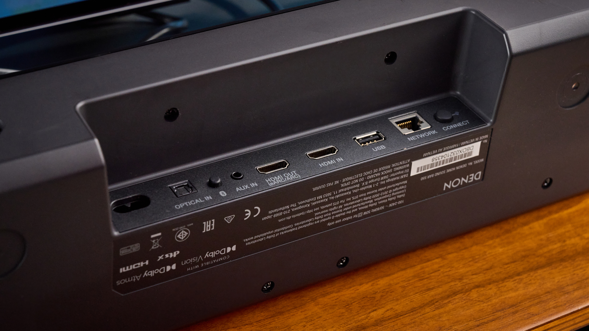 the denon home sound bar 550 with a gray mesh casing and touch controls for bluetooth on the top with a remote and smart home integration
