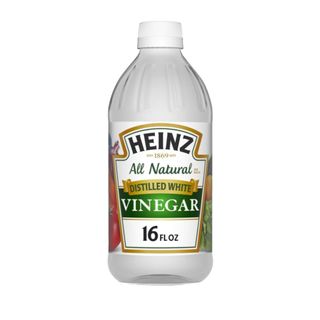 A bottle of white vinegar with a label that says 'Heinz all natural vinegar' on the front with green and gold boxes and a gold border around it