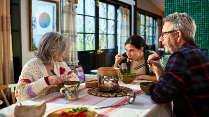 Parents sit at a dining room table with their adult child