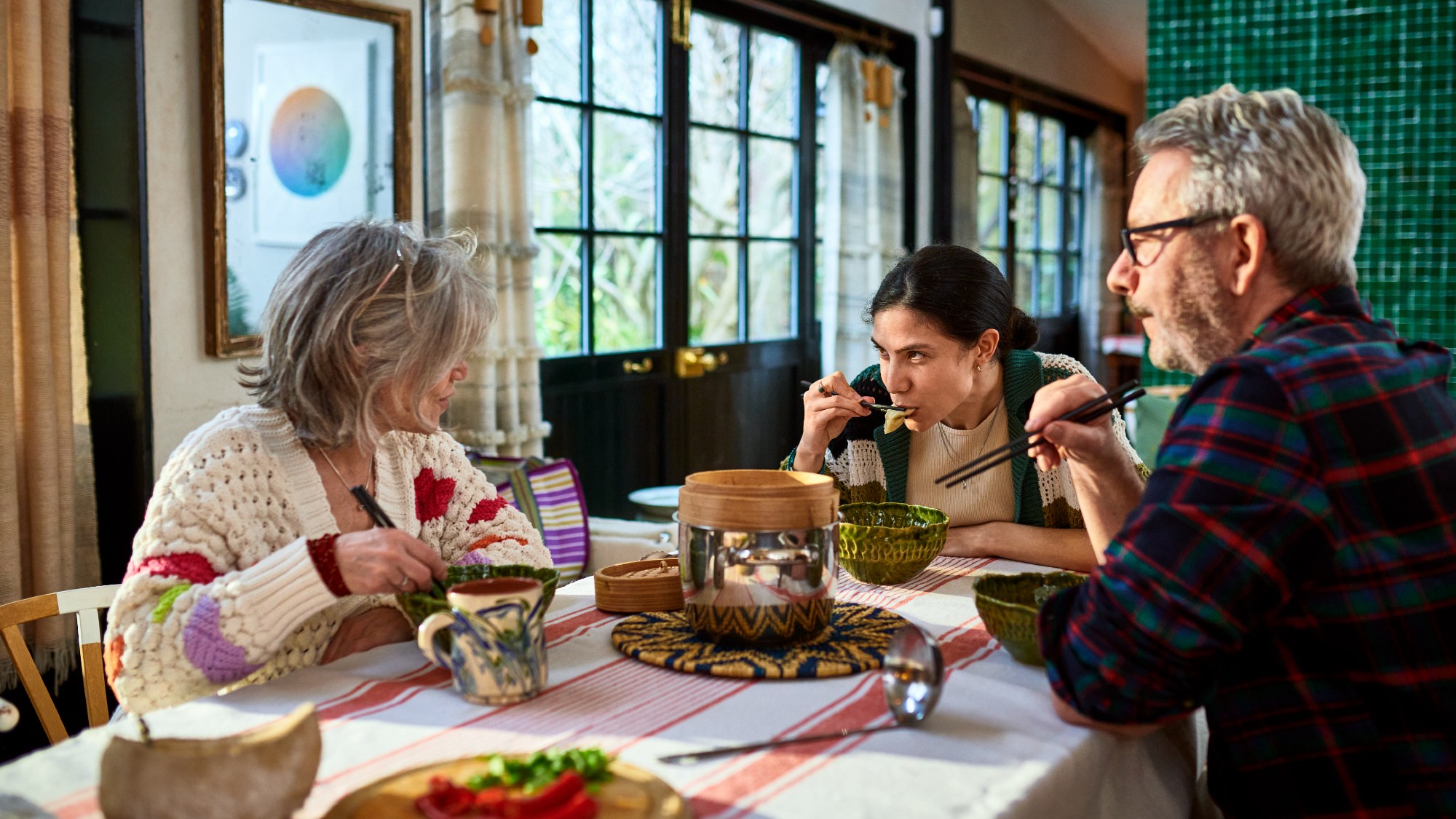 Parents sit at a dining room table with their adult child
