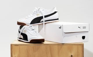 White Puma trainers positioned next to and on the box