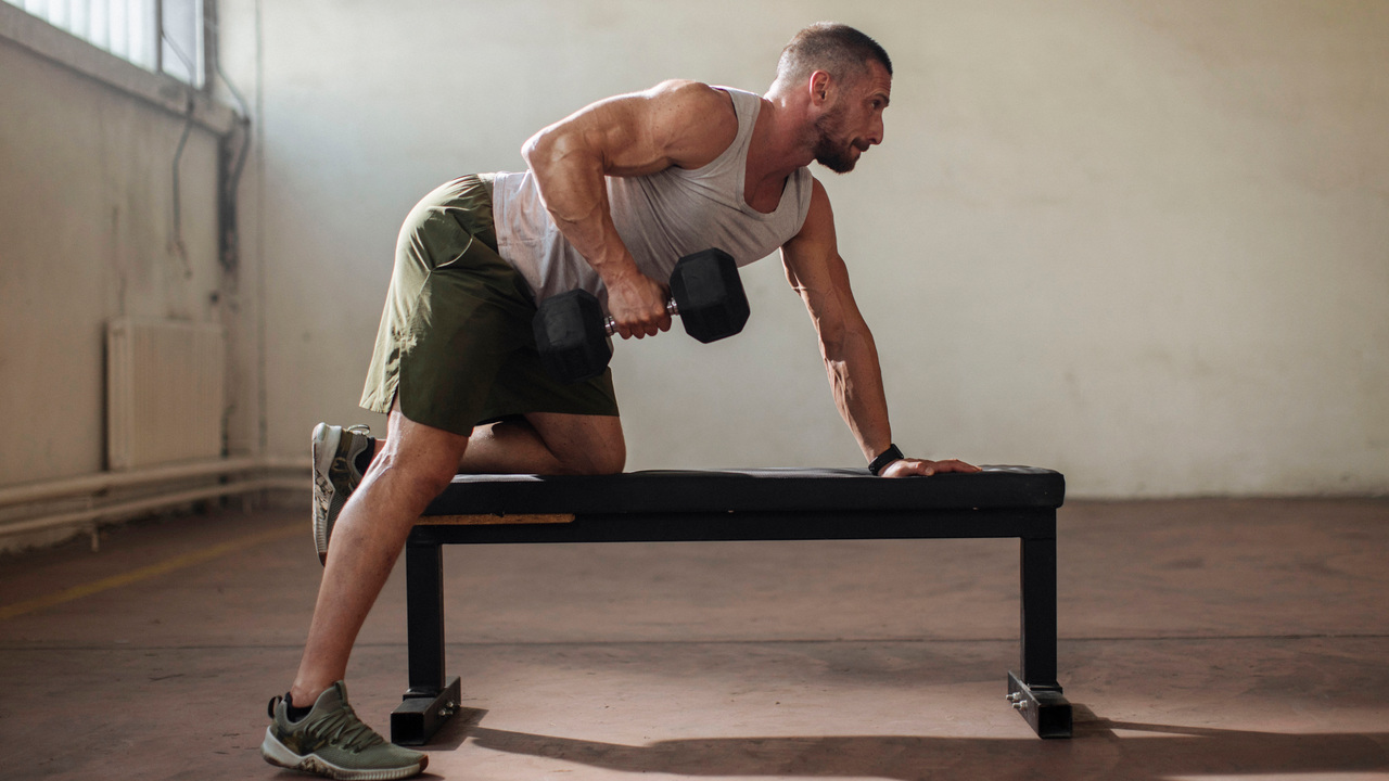 A man performing arm exercise tricep extensions on a weight bench