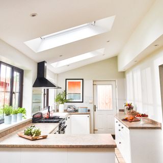 white kitchen with wooden worktops and peninsular unit and two skylights