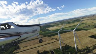 side view of plane flying near wind farm
