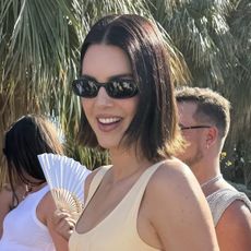 Kendall Jenner wears a butter yellow maxi dress and black sunglasses.