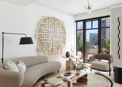 modern living room with curved beige couch, wall art, and a black lamp