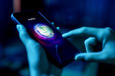 A person using a mobile phone to interact with an AI-powered chatbot, with the screen showing the word AI and vibrant neon lighting in blue tones.