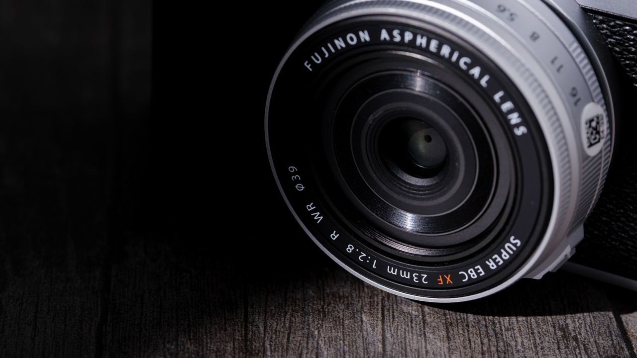 The Fujifilm XF 23mm f/2.8 R WR on a gray wood-like surface